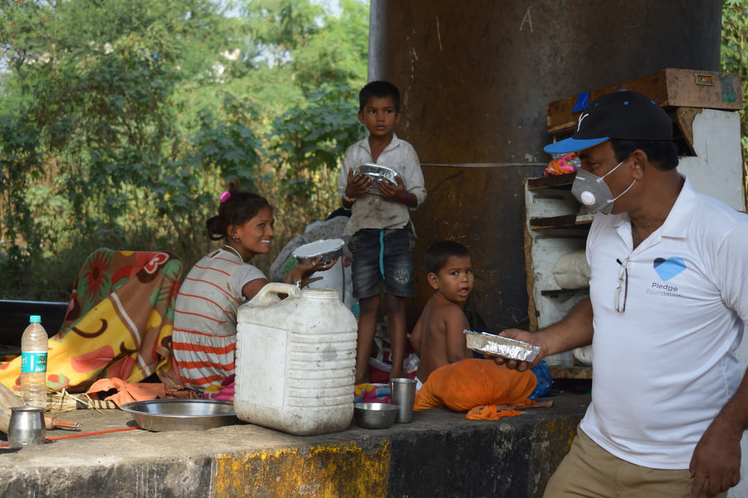 Volunteer handing out food packets under Food and Hunger Project by Pledge Foundation