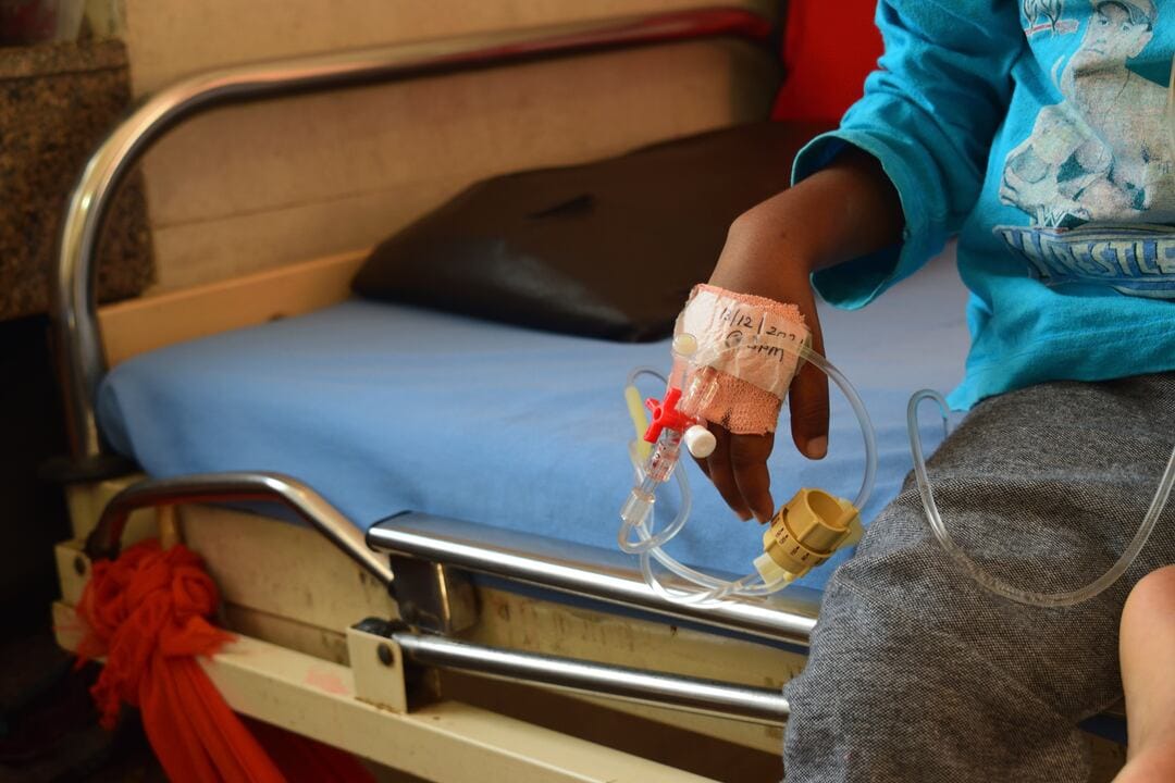 Child with saline solution on hand